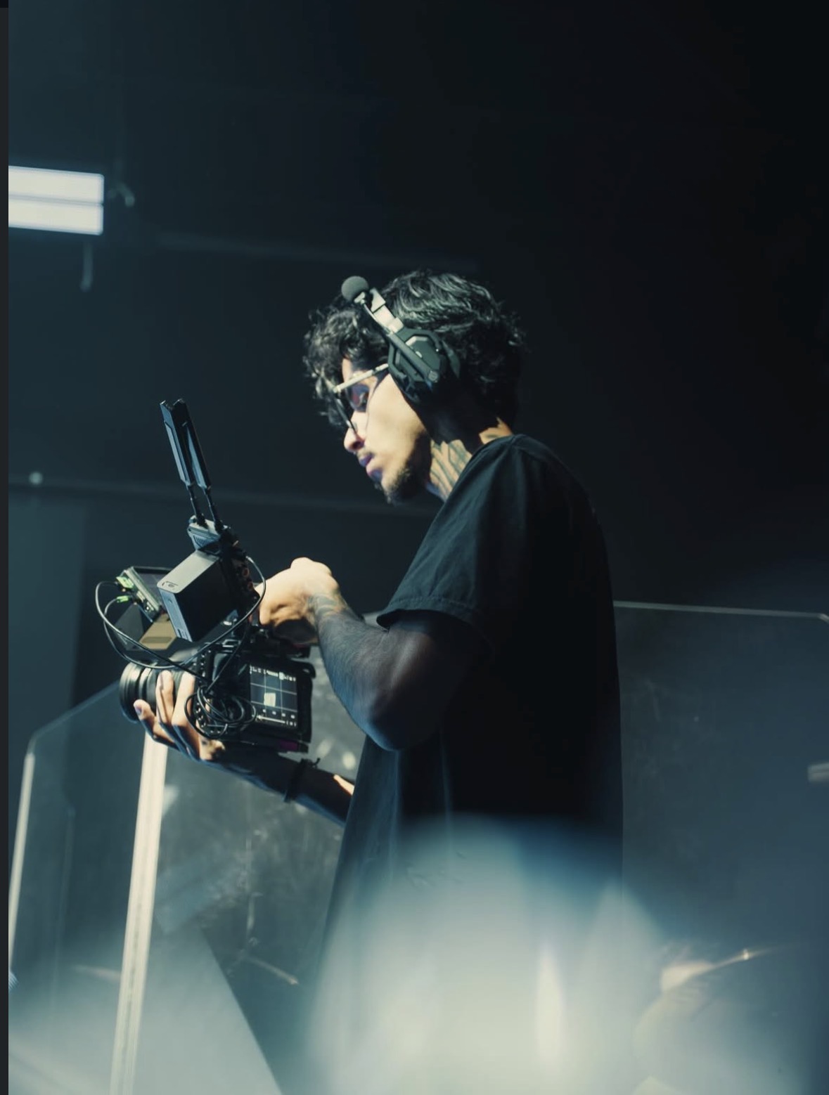 Luyd Almeida trabalhando com uma câmera de vídeo profissional, usando camiseta preta e headset
